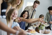 Family of adults and children gathering around dinner table. — Stock Photo