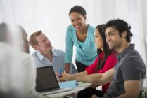 Multi ethnic group of people around table with laptop in meeting room in office. — Stock Photo