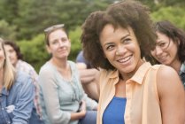 Young woman with afro smiling in group of friends outdoors. — Stock Photo