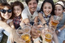 Gruppe gut gelaunter asiatischer Freunde stößt mit Bier im Park an. — Stockfoto