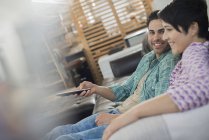Couple sitting on sofa at home and holding remote control device. — Stock Photo