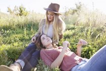 Two young adult women lying in grass in soft light. — Stock Photo
