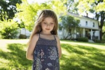 Kleines Mädchen steht mit den Händen auf dem Rücken im Garten. — Stockfoto