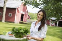 Young woman with long hair carrying bowl of fresh green salad leaves. — Stock Photo