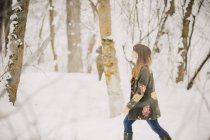 Side view of mid adult woman walking in snowy woodland. — Stock Photo