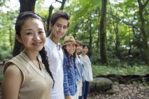Grupo de amigos asiáticos em pé em uma fileira na floresta verde . — Fotografia de Stock