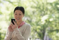 Mid adult woman checking smartphone in city park. — Stock Photo