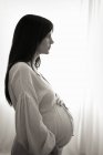 Vue latérale de la femme enceinte avec la main sur le ventre . — Photo de stock