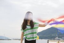 Frau am Strand in Kobe hält Papierschlangen, Japan. — Stockfoto