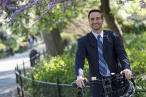 Man in business suit astride bicycle with helmet in city. — Stock Photo