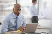 Homme d'affaires en chemise et cravate assis au bureau et utilisant un ordinateur portable au bureau . — Photo de stock