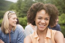 Mujer joven con afro sonriendo en grupo de amigos al aire libre . - foto de stock