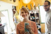 Man watching as woman holding stacked cups in antique store. — Stock Photo