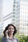 Jeune femme d'affaires en cardigan gris parlant au téléphone dans la rue . — Photo de stock
