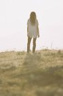 Woman in white shirt with long hair standing outdoors, rear view. — Stock Photo