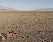 Cropped view of man lying on ground in desert of Death Valley National Park, California, USA. — Stock Photo