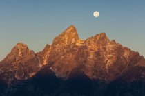 Jagged mountain range in Grand Teton national park with full moon in sky. — Stock Photo