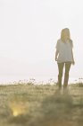 Woman in white shirt with long hair standing outdoors and looking away. — Stock Photo