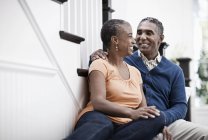 Mature man and woman sitting on stairs together at home. — Stock Photo