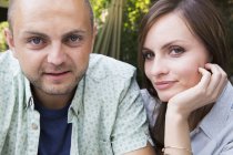 Couple sitting together outdoors and looking in camera. — Stock Photo