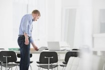 Man leaning down to office desk and using digital tablet. — Stock Photo