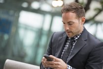 Man in business suit with short hair using smartphone on street. — Stock Photo