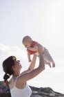 Mother playing with baby boy against blue sky. — Stock Photo