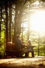 Family with daughter sitting at picnic table under trees in soft light. — Stock Photo