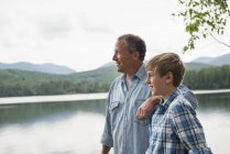Father and son standing outdoors on lake shore and looking at view. — Stock Photo
