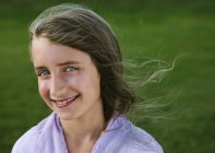 Retrato de sorrir menina idade elementar contra a grama verde . — Fotografia de Stock