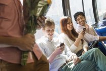 Grupo de personas montando en autobús urbano con smartphones y flores . - foto de stock