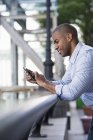 Mid adult man in shirt checking smartphone, side view. — Stock Photo