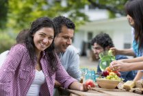 Mid adult woman holding peach at outdoor table with friends in garden. — Stock Photo