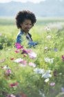 Жінка стоїть серед квітів, що ростуть у сільській місцевості . — стокове фото