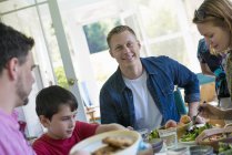 Man smiling and looking in camera with family and dinner table. — Stock Photo