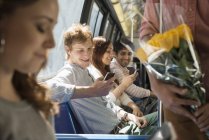 Gruppo di persone in autobus urbano con smartphone e fiori . — Foto stock