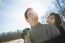 Hombre y una mujer abrazándose y riendo en el bosque invernal . - foto de stock
