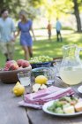 Servito tavolo esterno con frutta e limonata con persone in background . — Foto stock