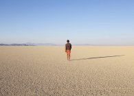 Homme marchant à travers le désert plat paysage — Photo de stock