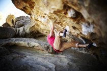 Man climbing on overhang of rock-face with minimum equipment. — Stock Photo