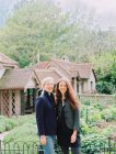 Two women posing in garden of historic house. — Stock Photo