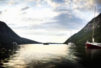 Boats, yacht and motorboat moored on calm lake in mountains. — Stock Photo