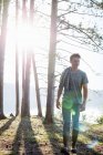 Front view of man walking on lakeside in forest. — Stock Photo