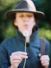 Woman blowing dandelion seed head outdoors. — Stock Photo