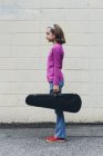 Допідліткова дівчина несе справу зі скрипкою на міській вулиці . — стокове фото