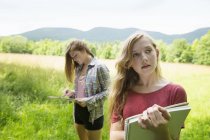 Дві дівчини-підлітки стоять на зеленій траві і малюють в ескізах . — стокове фото