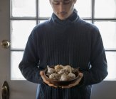Молодой человек держит миску луковиц чеснока . — стоковое фото