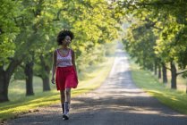 Woman walking at country road in sunny park. — Stock Photo