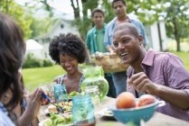Young people having meal in country garden. — Stock Photo