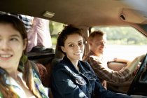 Man driving car with young women on countryside road. — Stock Photo
